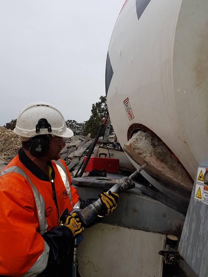 Hardened concrete being removed from a mixer drum